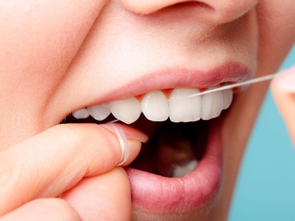 Frau zeigt richtige Anwendung der Zahnseide zur Reinigung der Zähne